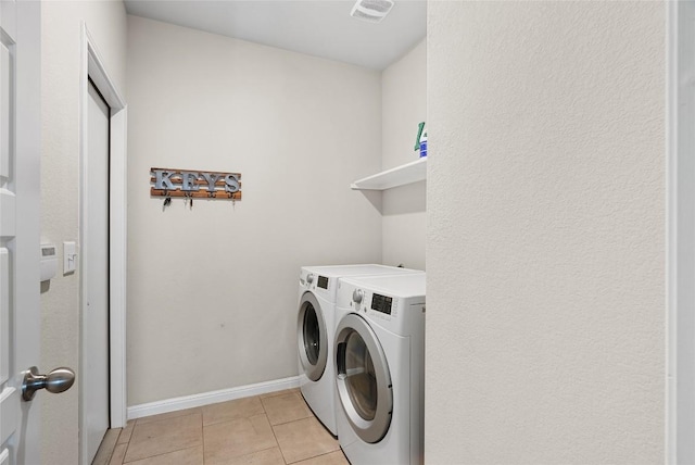 laundry room with light tile patterned flooring and washer and clothes dryer