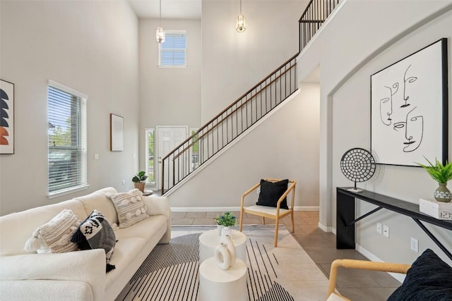 living room with baseboards, stairs, a high ceiling, and tile patterned floors