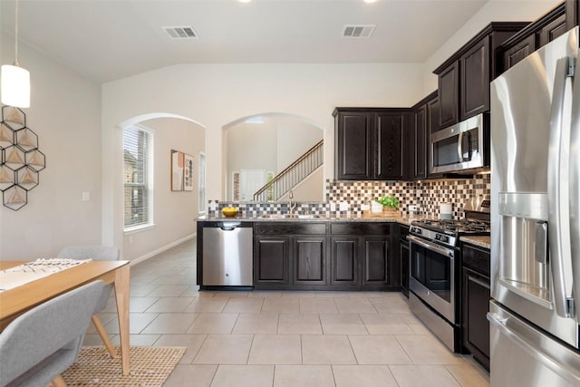 kitchen featuring visible vents, tasteful backsplash, arched walkways, and appliances with stainless steel finishes