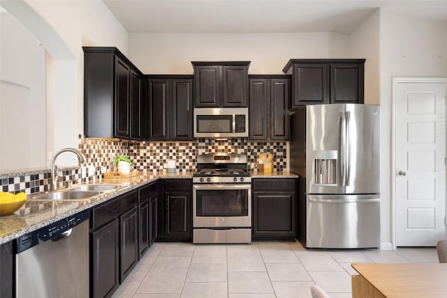 kitchen with backsplash, light tile patterned floors, a sink, and stainless steel appliances