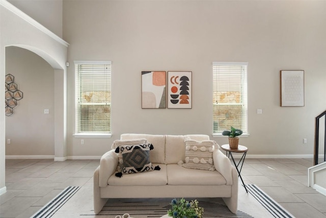 living area featuring baseboards, arched walkways, and light tile patterned floors