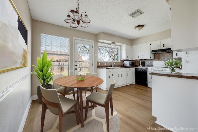 kitchen featuring gas range gas stove, black dishwasher, white cabinets, decorative backsplash, and light wood-type flooring