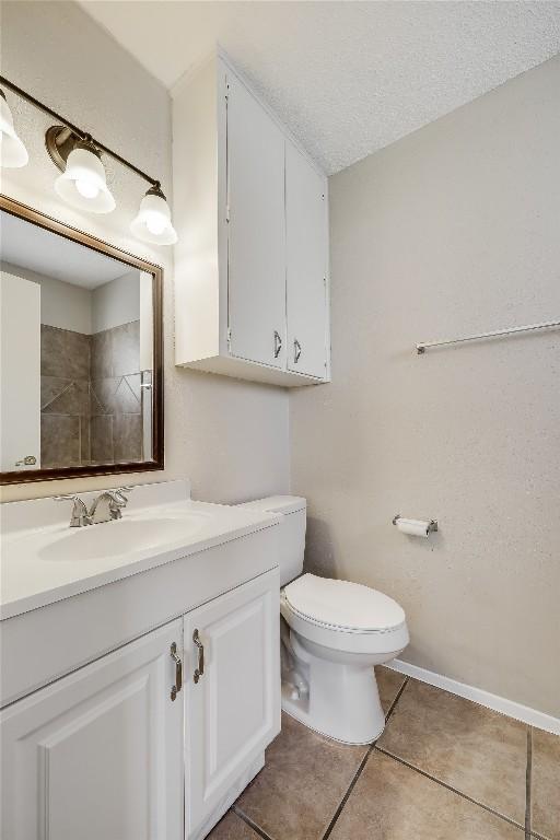 bathroom with vanity, tile patterned flooring, a textured ceiling, and toilet