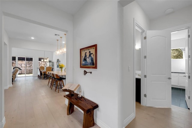 corridor featuring an inviting chandelier and light hardwood / wood-style flooring