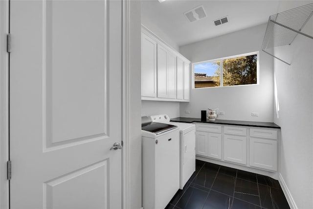 clothes washing area with dark tile patterned flooring, washer and clothes dryer, and cabinets