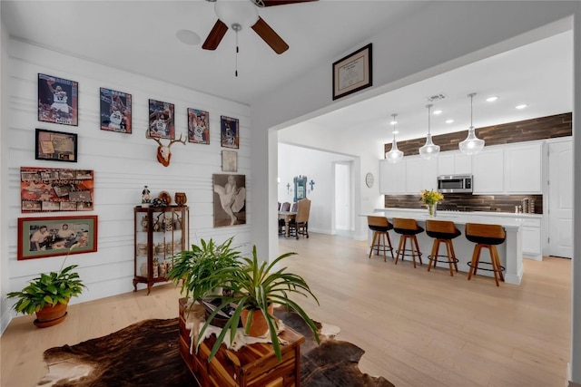 living room with ceiling fan and light hardwood / wood-style floors