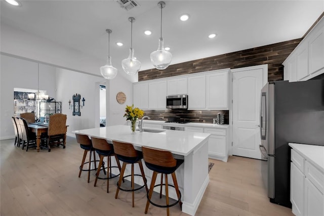 kitchen featuring sink, tasteful backsplash, an island with sink, pendant lighting, and stainless steel appliances