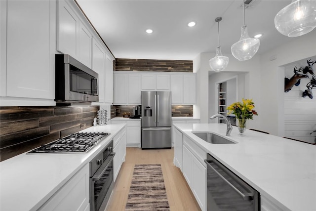 kitchen with white cabinetry, appliances with stainless steel finishes, decorative light fixtures, and sink