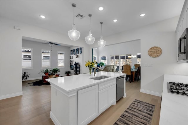 kitchen featuring sink, white cabinetry, a center island with sink, stainless steel appliances, and light hardwood / wood-style floors