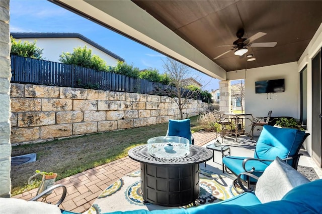 view of patio / terrace featuring ceiling fan and an outdoor living space with a fire pit