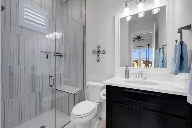 bathroom with an enclosed shower, vanity, toilet, and ceiling fan