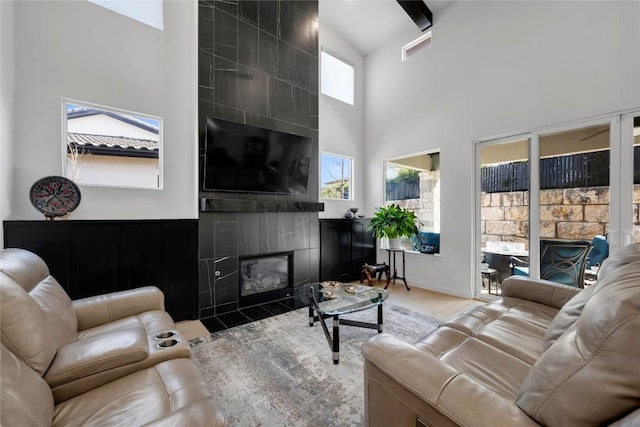 living room with a towering ceiling, a fireplace, and hardwood / wood-style flooring