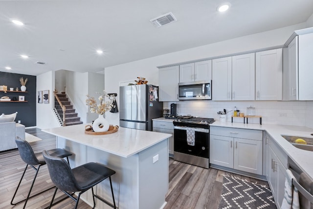 kitchen featuring a center island, visible vents, decorative backsplash, appliances with stainless steel finishes, and wood finished floors