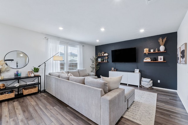 living room with dark wood-style floors, an accent wall, recessed lighting, and baseboards