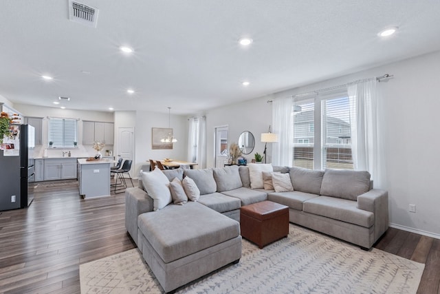 living room with light wood-type flooring, baseboards, visible vents, and recessed lighting