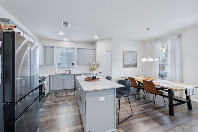 kitchen with a center island, stainless steel appliances, light countertops, pendant lighting, and a sink