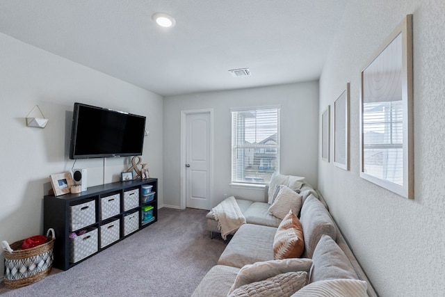 carpeted living room with visible vents and a textured wall