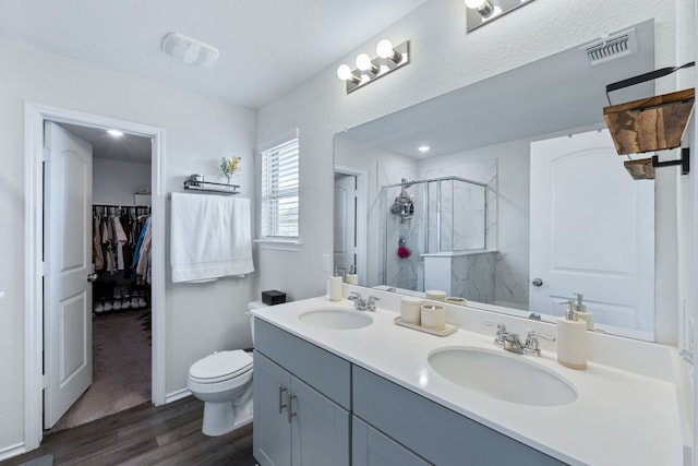 bathroom with a stall shower, visible vents, a sink, and wood finished floors