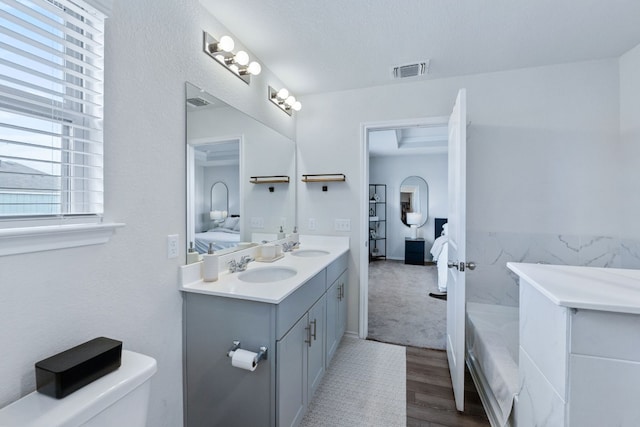 full bath with toilet, a sink, visible vents, double vanity, and ensuite bath