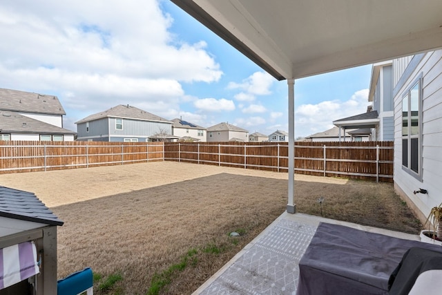 view of yard with a patio area, a fenced backyard, and a residential view