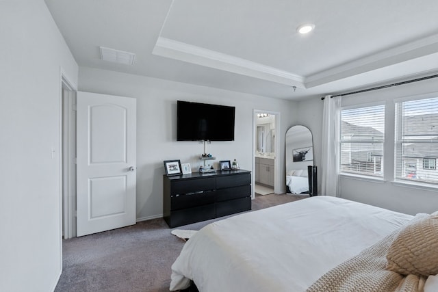 carpeted bedroom with ensuite bath, baseboards, visible vents, and a tray ceiling