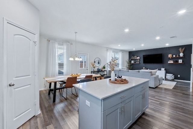 kitchen with open floor plan, light countertops, hanging light fixtures, a center island, and dark wood finished floors