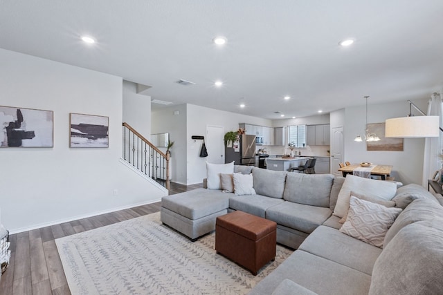 living area featuring recessed lighting, visible vents, baseboards, stairs, and light wood-type flooring