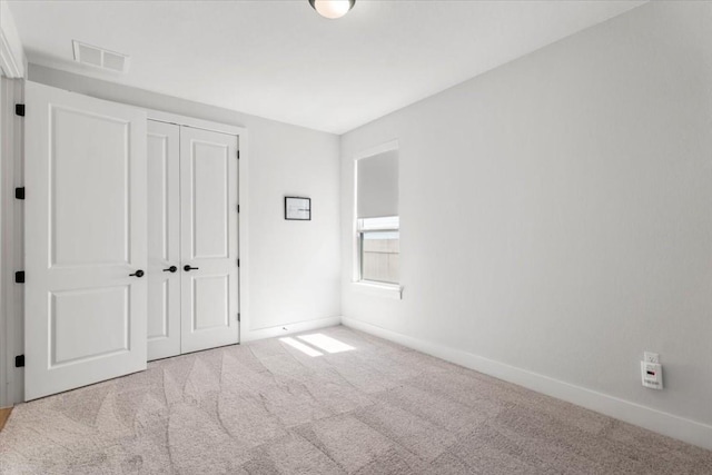 unfurnished bedroom with light colored carpet and a closet