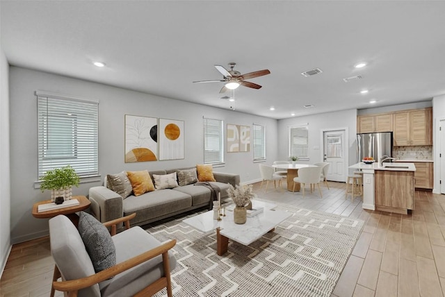 living room featuring sink, ceiling fan, and light hardwood / wood-style flooring