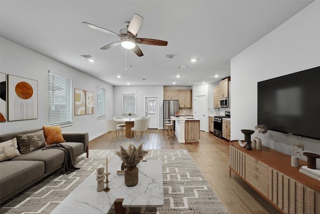 living room with light wood finished floors, visible vents, recessed lighting, and ceiling fan