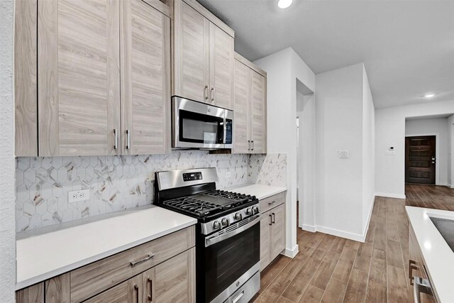 205 Ashby Dr, Hutto, TX 78634 - kitchen with appliances with stainless steel finishes, wood finished floors, baseboards, recessed lighting, and tasteful backsplash