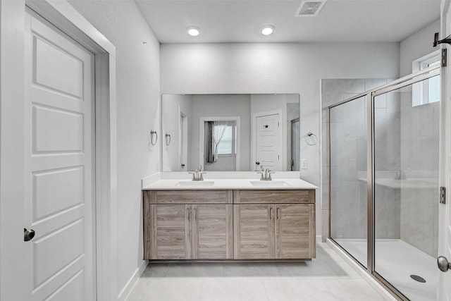 bathroom featuring a shower stall, a healthy amount of sunlight, a sink, and visible vents