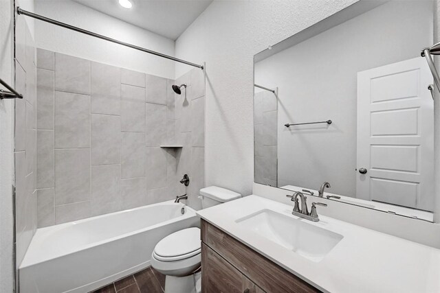 full bathroom with tiled shower / bath combo, vanity, hardwood / wood-style floors, and toilet