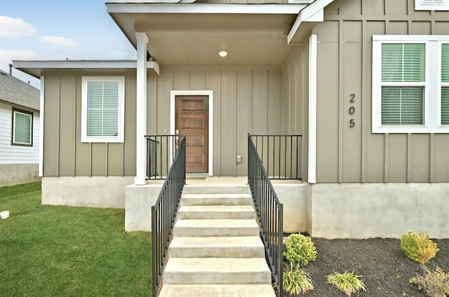 205 Ashby Dr, Hutto, TX 78634 - view of exterior entry featuring board and batten siding and a lawn