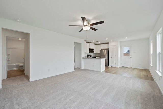 unfurnished living room with light carpet and ceiling fan