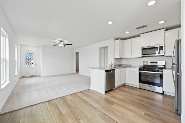 kitchen with stainless steel appliances, light hardwood / wood-style flooring, white cabinets, and kitchen peninsula