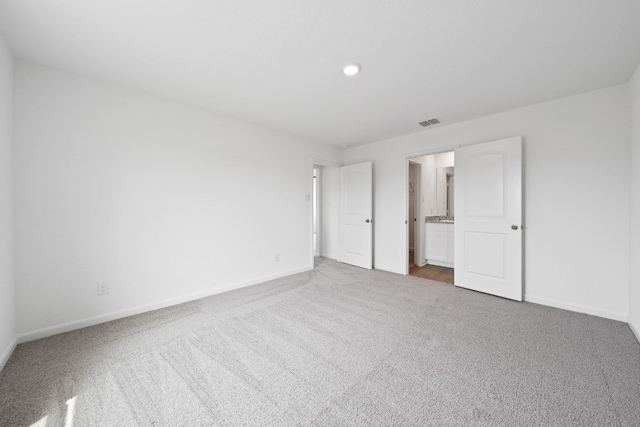 unfurnished bedroom featuring ensuite bath and carpet floors