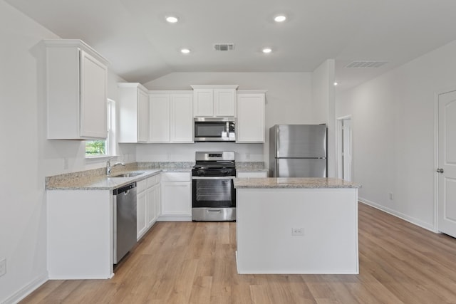 kitchen featuring white cabinetry, a center island, stainless steel appliances, light stone countertops, and light hardwood / wood-style flooring