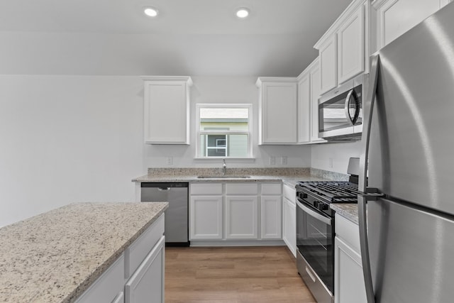 kitchen with light stone counters, sink, stainless steel appliances, and white cabinets