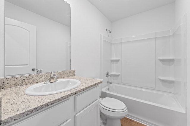 full bathroom featuring vanity, hardwood / wood-style floors, washtub / shower combination, and toilet