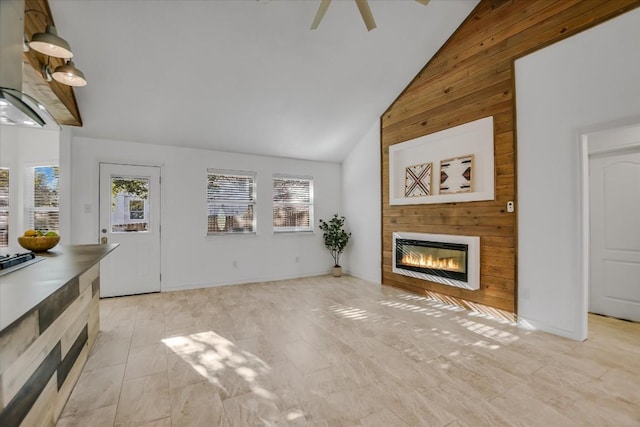 unfurnished living room featuring a healthy amount of sunlight, a large fireplace, ceiling fan, and high vaulted ceiling