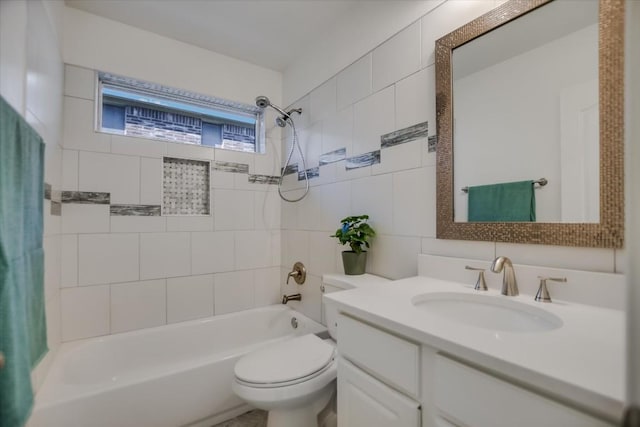 full bathroom featuring tiled shower / bath, vanity, toilet, and tile walls