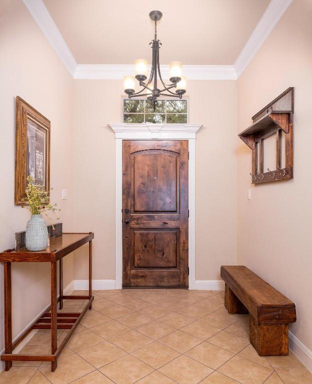 foyer entrance featuring a notable chandelier, crown molding, and light tile patterned floors