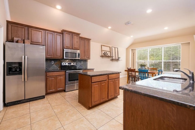 kitchen featuring sink, light tile patterned floors, stainless steel appliances, a kitchen island with sink, and decorative backsplash