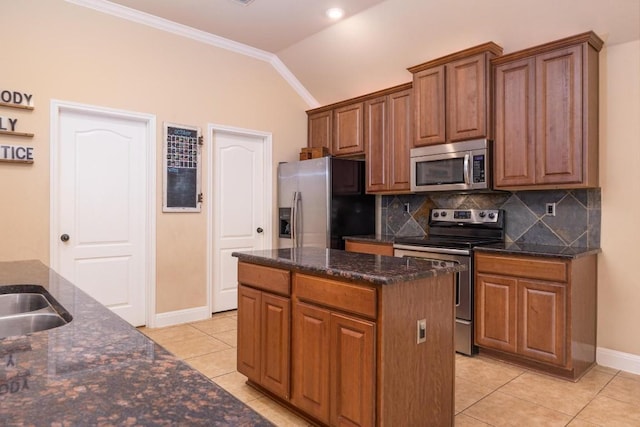 kitchen featuring lofted ceiling, crown molding, a kitchen island, stainless steel appliances, and backsplash