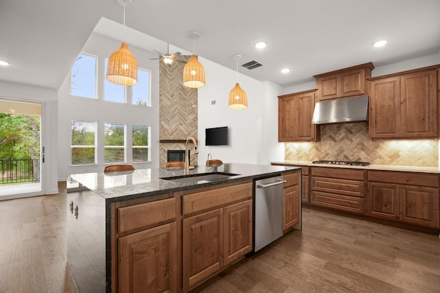 kitchen featuring appliances with stainless steel finishes, decorative light fixtures, sink, and a center island with sink