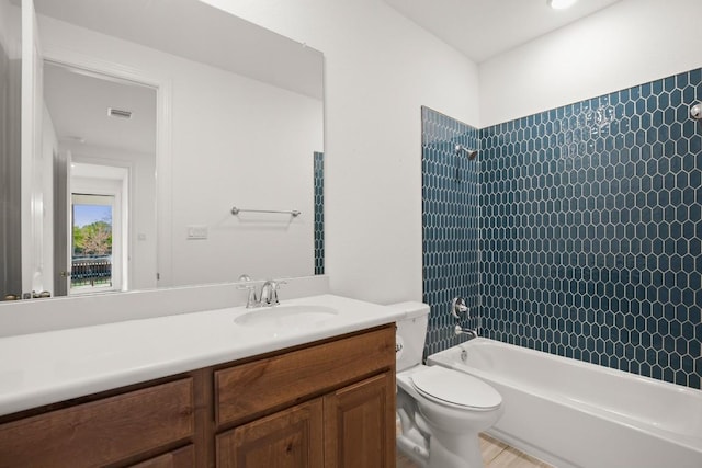 full bathroom with vanity, tiled shower / bath combo, and toilet