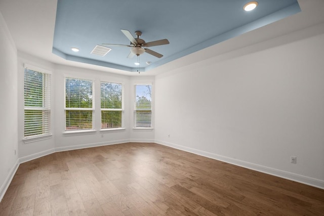 spare room with a raised ceiling, hardwood / wood-style flooring, and ceiling fan