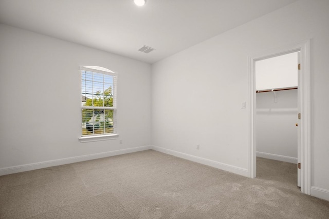 unfurnished bedroom with light colored carpet, a spacious closet, and a closet