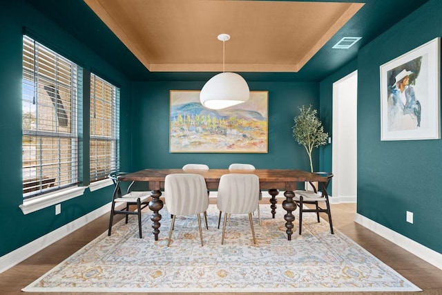 dining area featuring dark hardwood / wood-style floors and a tray ceiling